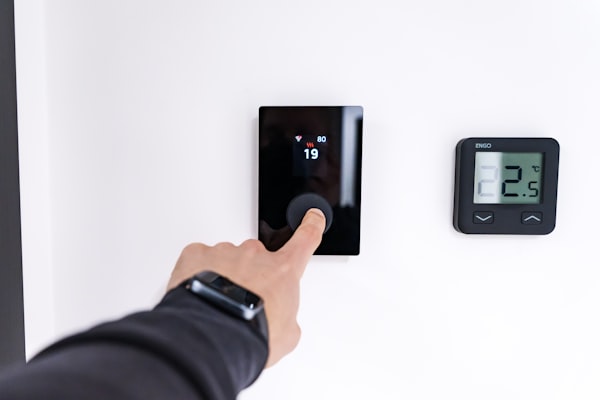 Hand adjusting a modern digital thermostat on wall